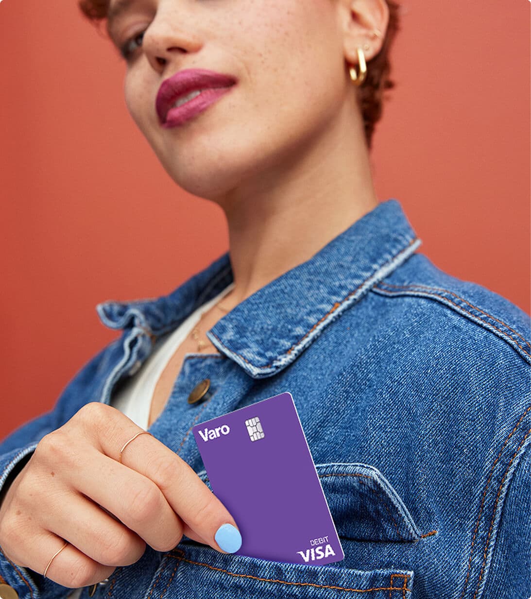 Woman placing Varo Visa debit card in the pocket of her jean jacket